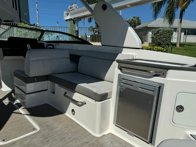 Slide: The Image of 2020 Sea Ray SDX 290 Outboard interior with seating and mini fridge, sunny day. - 16