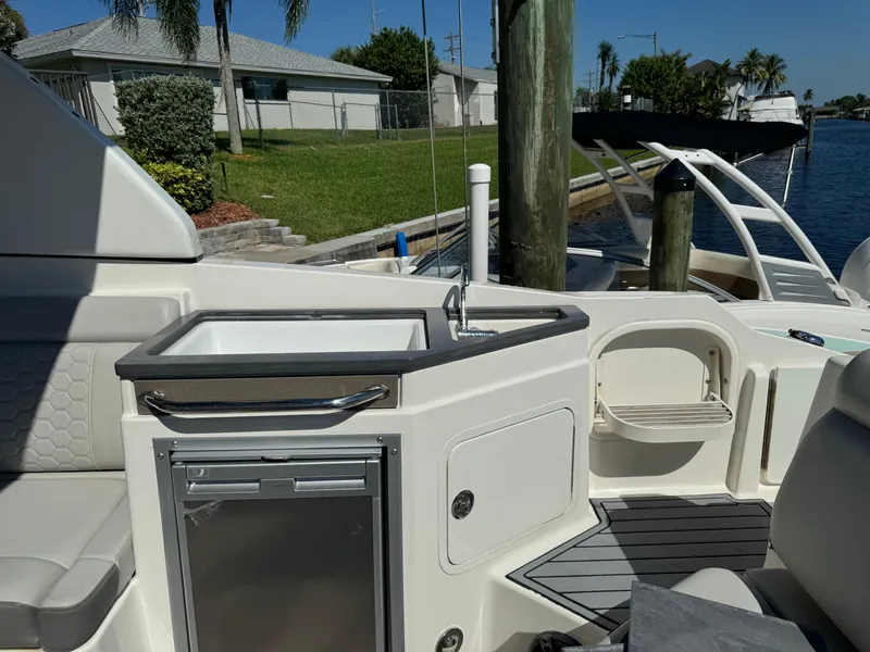 Slide: The Image of 2020 Sea Ray SDX 290 Outboard boat interior with sink and seating by the dock. - 17