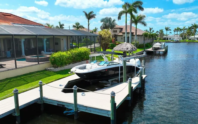 Slide: The Image of 2020 Sea Ray SDX 290 Outboard docked by waterfront homes, palm trees, and clear skies. - 4