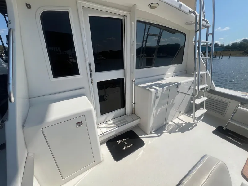 Slide: The Image of 1996 Egg Harbor Convertible yacht deck with ladder and door, docked by the water. - 14