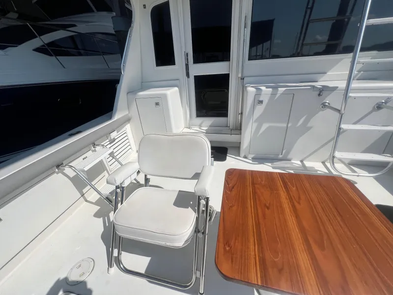 Slide: The Image of 1996 Egg Harbor Convertible yacht deck with white chair and wooden table. - 16