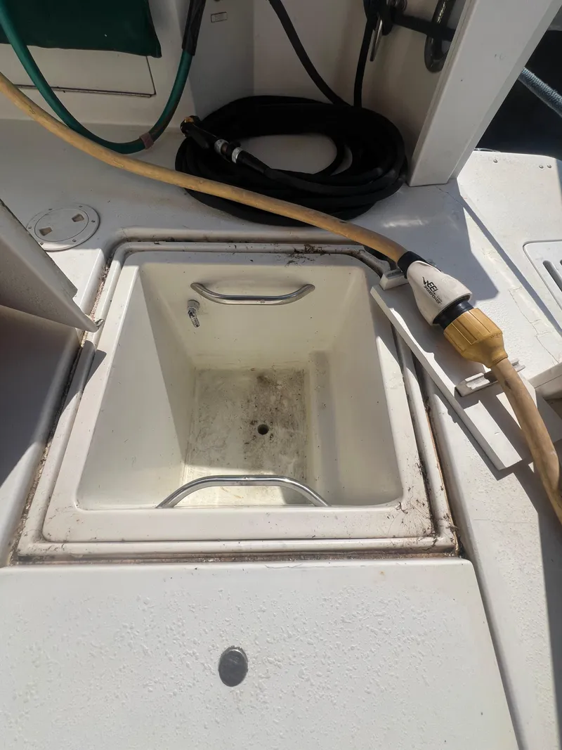 Slide: The Image of 1996 Egg Harbor Convertible boat deck with storage compartment and hoses. - 18