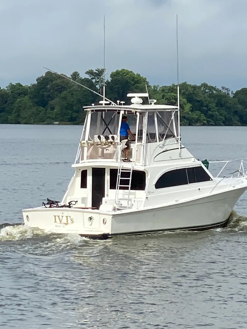 Slide: The Image of 1996 Egg Harbor Convertible boat cruising on a calm river with lush green trees. - 3