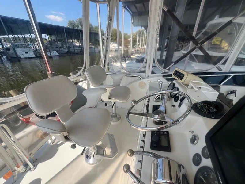 Slide: The Image of 1996 Egg Harbor Convertible boat cockpit with steering wheel and controls, docked at marina. - 36
