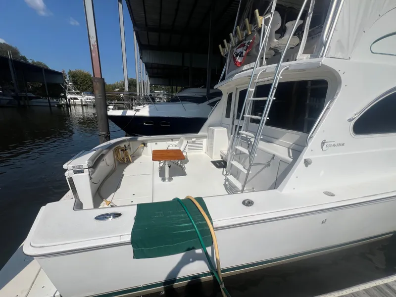 Slide: The Image of 1996 Egg Harbor Convertible yacht docked, featuring spacious deck and ladder under a covered marina. - 8