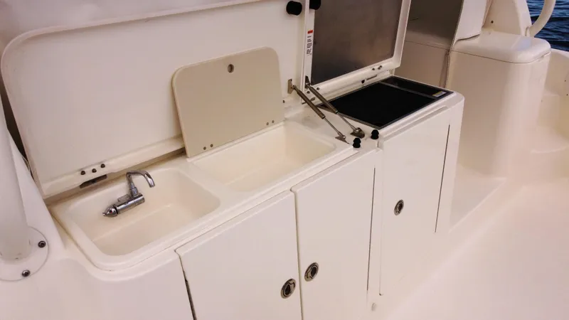 Slide: The Image of 2020 Pursuit OS 385 Offshore boat kitchen area with sink and storage cabinets. - 11