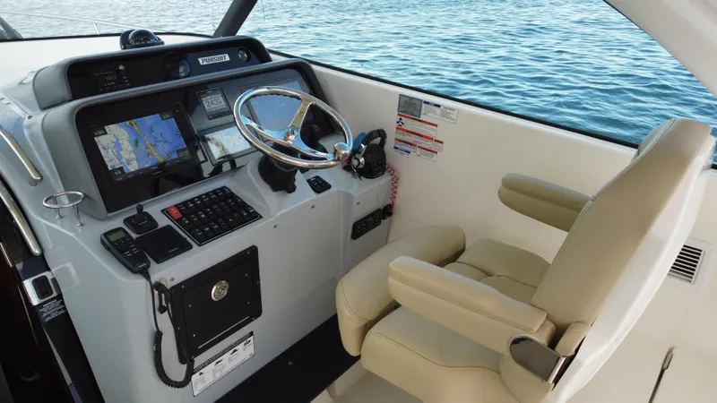 Slide: The Image of 2020 Pursuit OS 385 Offshore helm with navigation equipment and beige captain's chair. - 14