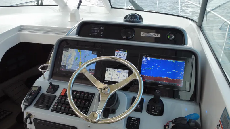 Slide: The Image of 2020 Pursuit OS 385 Offshore boat dashboard with navigation screens and steering wheel. - 18