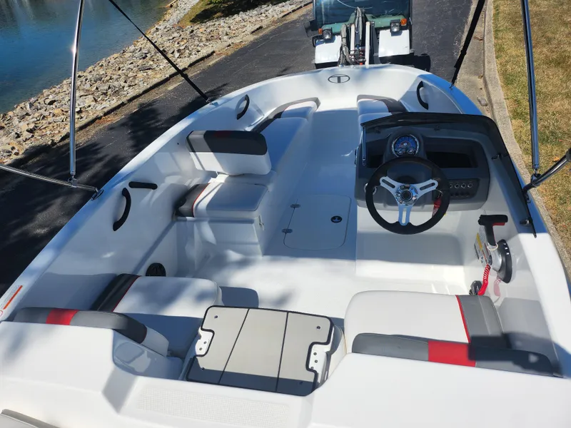 Slide: The Image of 2021 Tahoe T16 boat interior with seating and steering wheel, parked near a waterway. - 10
