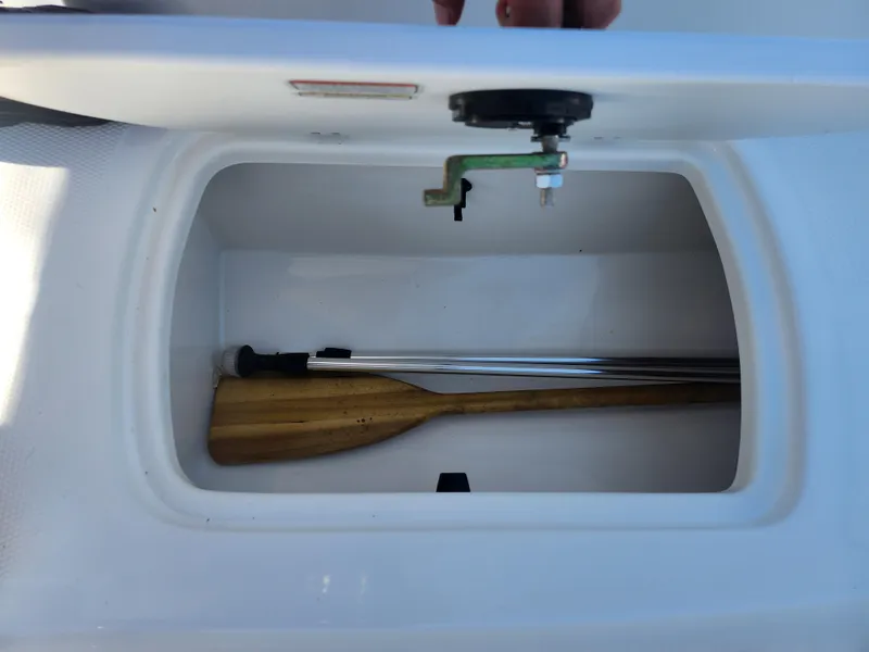 Slide: The Image of Storage compartment in 2021 Tahoe T16 boat with wooden paddle and metal pole. - 14