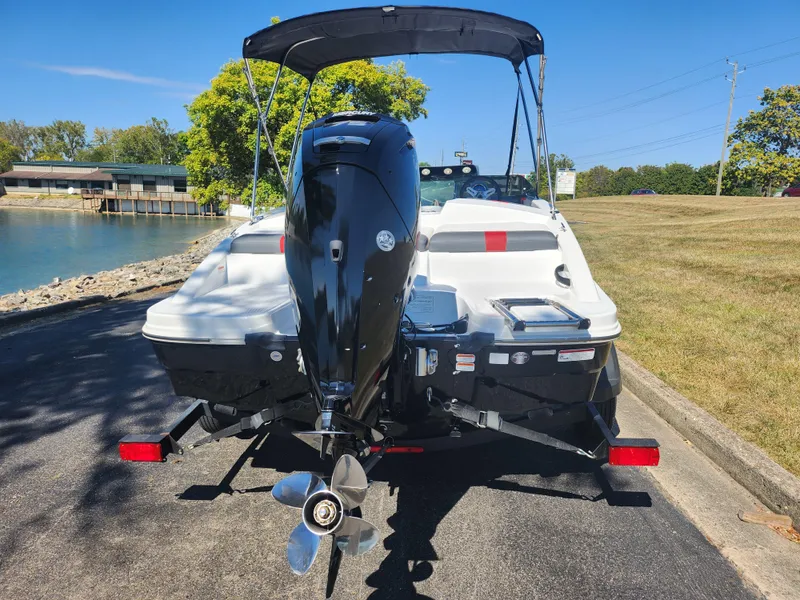 Slide: The Image of 2021 Tahoe T16 boat on trailer by lakeside, featuring outboard motor and canopy. - 2