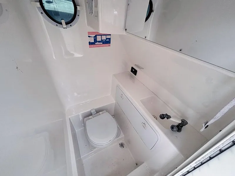 Slide: The Image of 2003 Marlago FS35 boat bathroom with toilet, sink, and porthole window. - 27