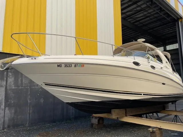 Slide: The Image of 2001 Sea Ray 280 Sundancer boat in storage, yellow and white building background. - 0