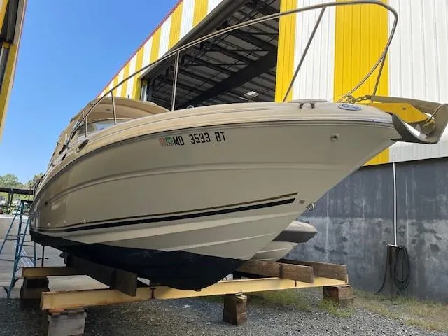 Slide: The Image of 2001 Sea Ray 280 Sundancer boat on dry dock, yellow and white building background. - 1