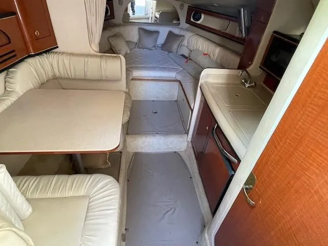 Slide: The Image of Interior of 2001 Sea Ray 280 Sundancer boat with seating, table, and kitchenette. - 17