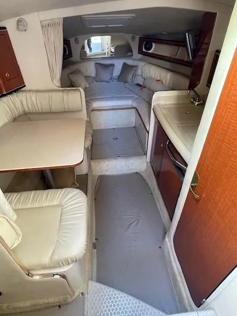 Slide: The Image of Interior of 2001 Sea Ray 280 Sundancer, featuring cozy seating and compact kitchenette. - 18