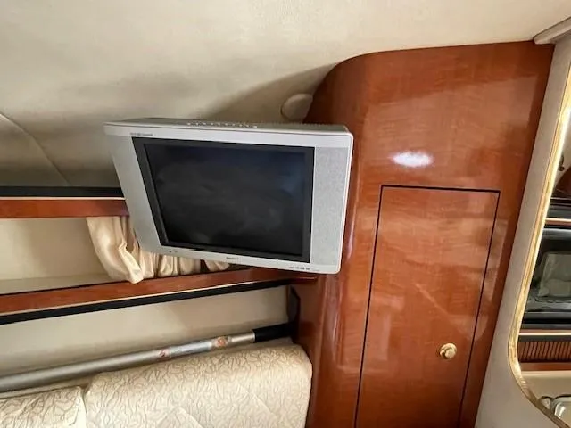 Slide: The Image of 2001 Sea Ray 280 Sundancer interior with mounted TV and wooden cabinetry. - 29