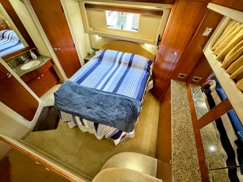Slide: The Image of Luxurious 2005 Sea Ray 390 Motor Yacht bedroom with striped bedding and wood accents. - 39