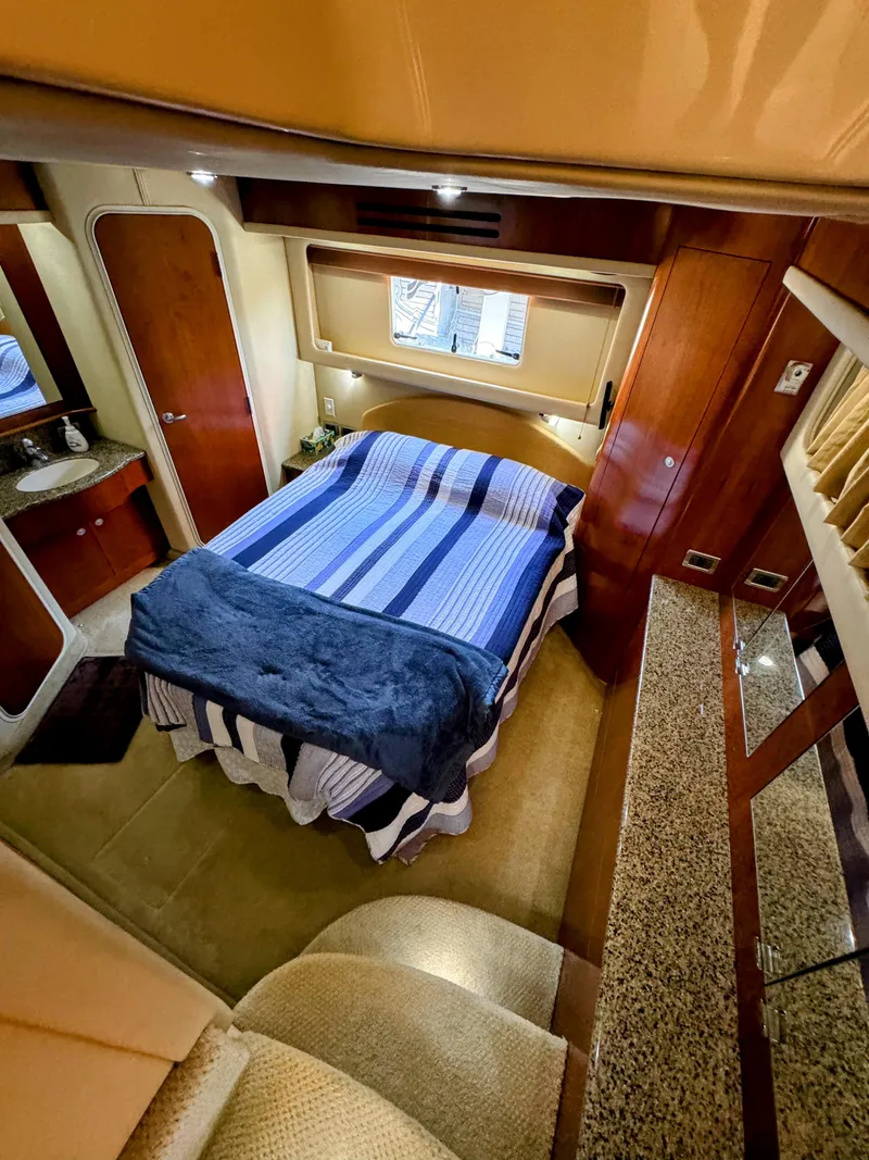 Slide: The Image of Luxurious 2005 Sea Ray 390 Motor Yacht bedroom with striped bedding and elegant wood finishes. - 42