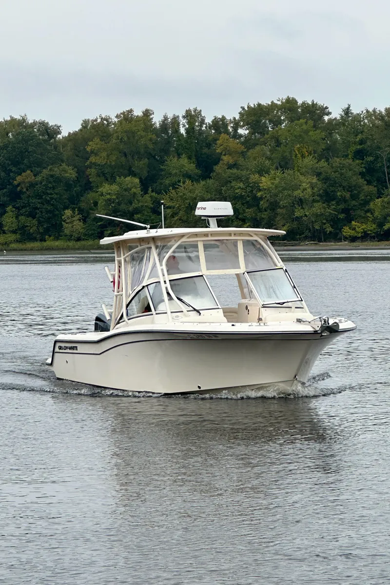 Slide: The Image of 2022 Grady-White Freedom 235 boat cruising on a calm lake with forested shoreline. - 0