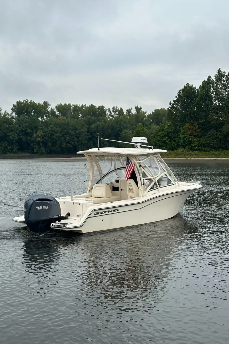 Slide: The Image of 2022 Grady-White Freedom 235 boat on a calm lake with trees in the background. - 2