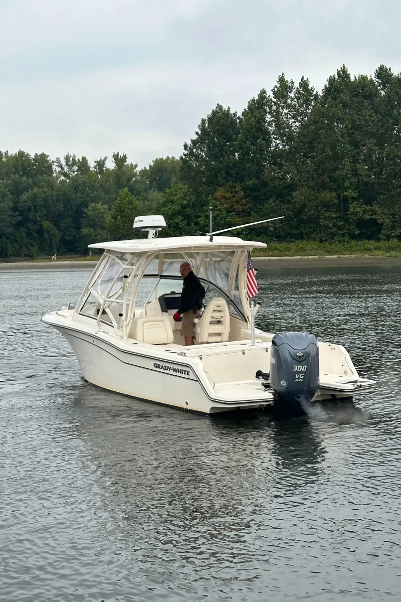 Slide: The Image of 2022 Grady-White Freedom 235 boat on a calm lake with trees in the background. - 4