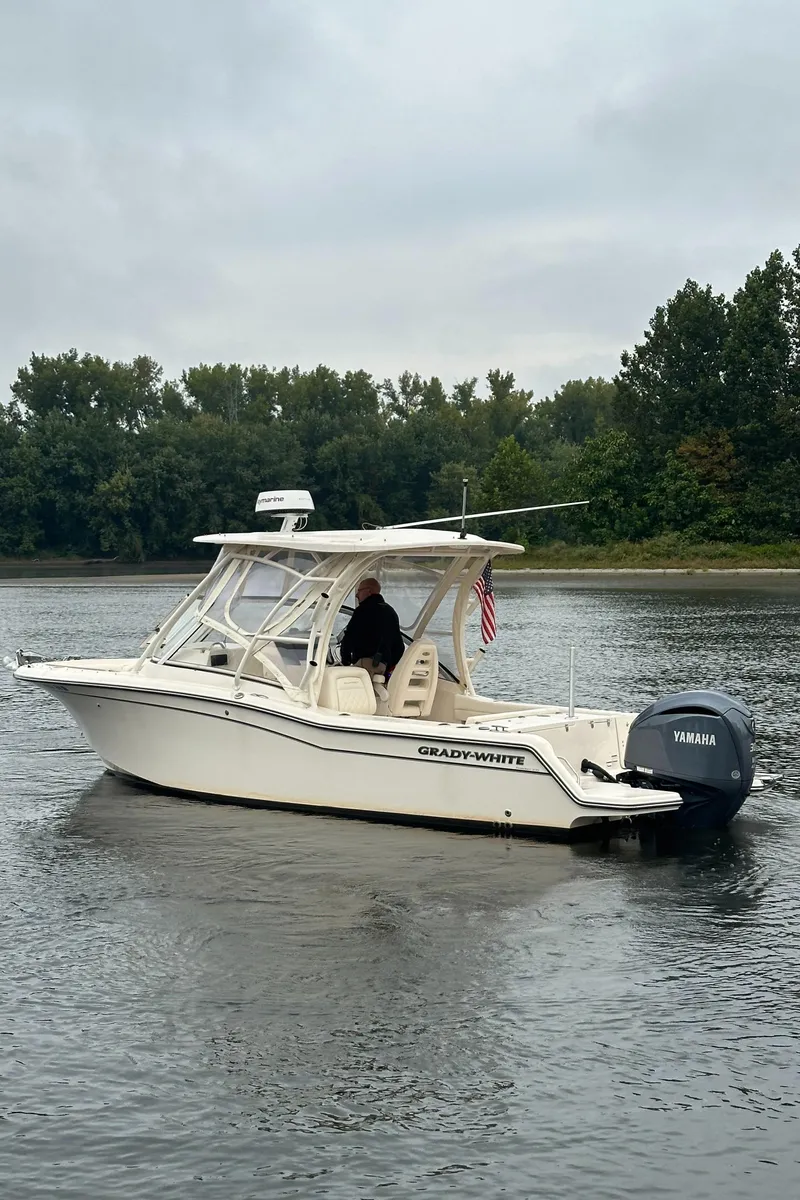 Slide: The Image of 2022 Grady-White Freedom 235 boat on a calm lake with trees in the background. - 5