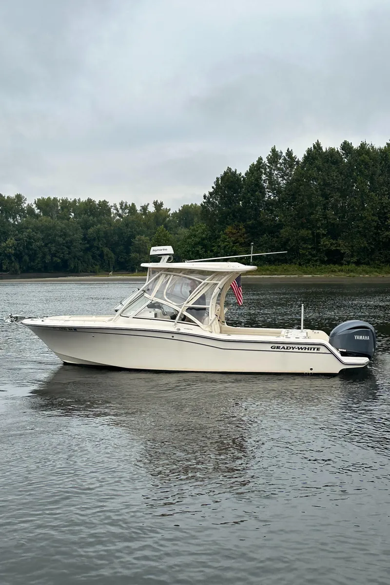 Slide: The Image of 2022 Grady-White Freedom 235 boat on a calm lake with forested background. - 6
