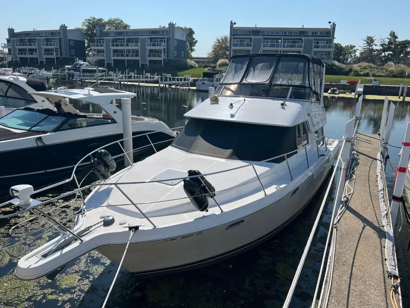 The Image of 1999 Carver 370 Voyager docked at marina with modern buildings in background. - 0