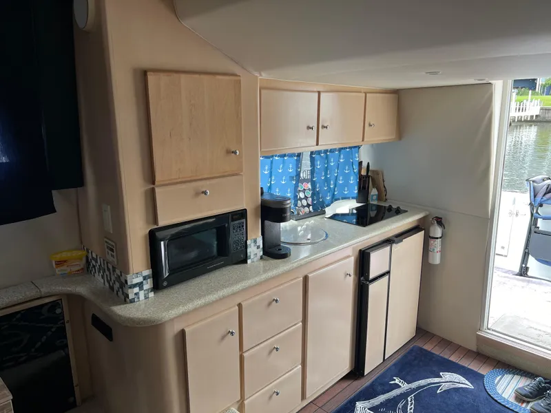 Slide: The Image of 1999 Carver 370 Voyager yacht kitchen with cabinets, microwave, and mini-fridge. - 16
