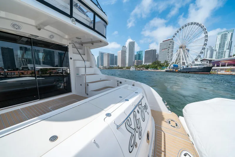 Slide: The Image of 2006 Sea Ray 58 Sedan Bridge yacht docked with city skyline and Ferris wheel in background. - 25