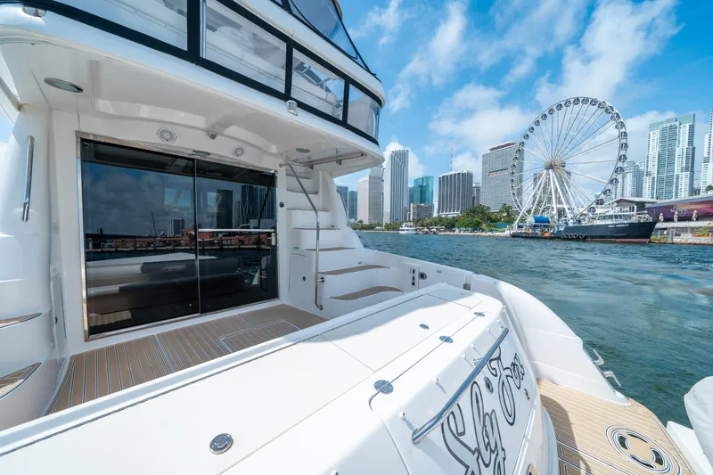 Slide: The Image of 2006 Sea Ray 58 Sedan Bridge yacht docked with city skyline and Ferris wheel in background. - 26