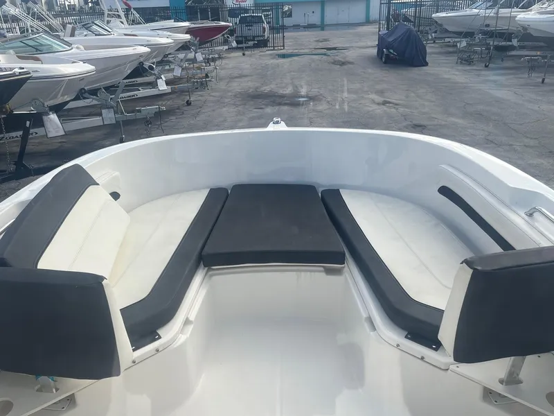 Slide: The Image of 2022 Bayliner Trophy T22CC boat interior with cushioned seating in a marina. - 2
