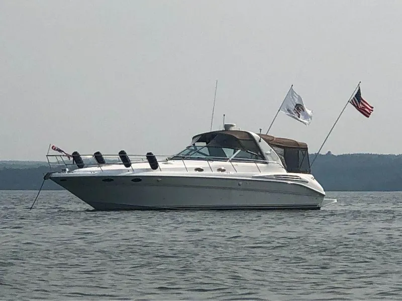 The Image of 1997 Sea Ray 400 Sundancer yacht on calm water with flags. - 0