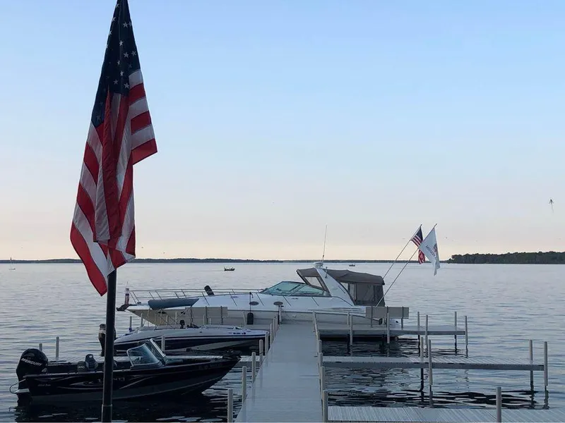 Slide: The Image of Docked 1997 Sea Ray 400 Sundancer with American flag, calm waters, and clear sky. - 17