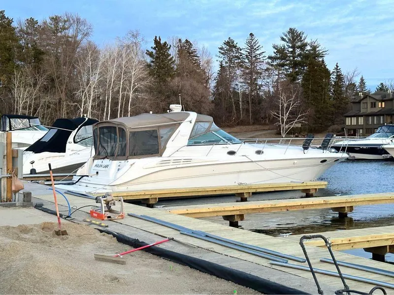 Slide: The Image of 1997 Sea Ray 400 Sundancer docked by a serene lakeside with trees in the background. - 3