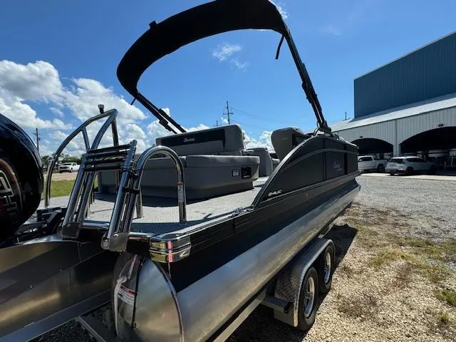 Slide: The Image of 2025 Barletta Aria 24UC pontoon boat on trailer, parked outdoors under a clear sky. - 10