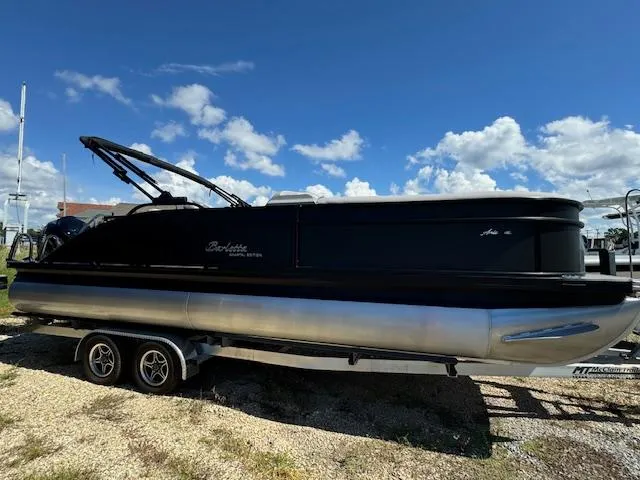 Slide: The Image of 2025 Barletta Aria 24UC pontoon boat on trailer under blue sky. - 11