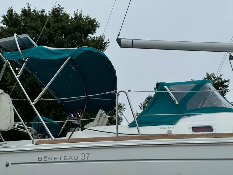Slide: The Image of 2008 Beneteau Oceanis 37 sailboat with teal canopy and cover, docked outdoors. - 22