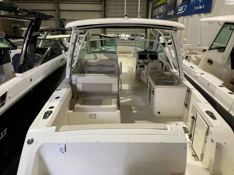 Slide: The Image of 2024 Boston Whaler 320 Vantage boat interior, showcasing seating and helm area in a showroom. - 3
