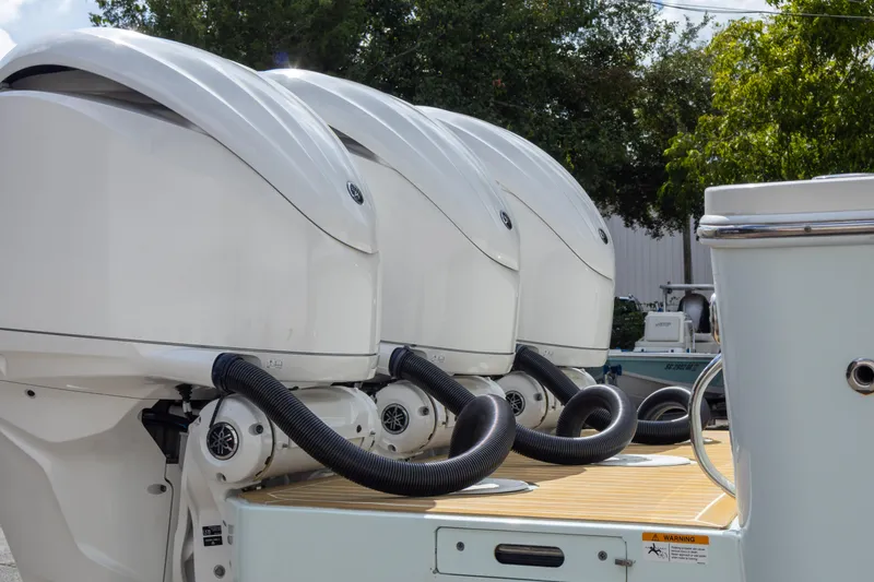 Slide: The Image of Triple outboard motors on a 2023 Regulator 34 boat, docked outdoors. - 12