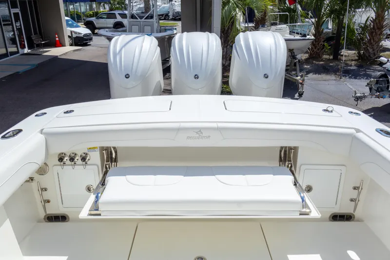 Slide: The Image of 2023 Regulator 34 boat with triple outboard engines, white interior, and fishing amenities. - 24