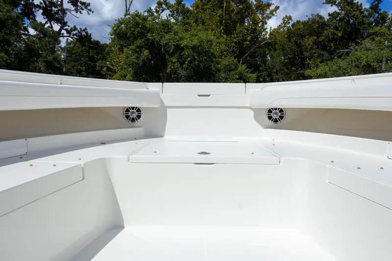 Slide: The Image of 2023 Regulator 34 boat interior with white seating and speakers, surrounded by trees. - 28