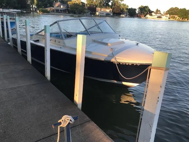 Slide: The Image of 1970 Chris-Craft 25 Lancer boat docked by a serene lakeside. - 2