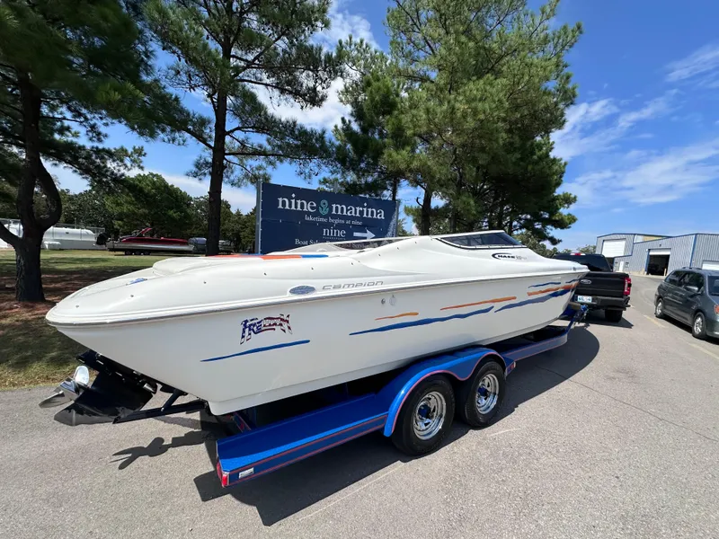 Slide: The Image of 1997 Campion Chase 910 ZRI boat on trailer at marina, surrounded by trees and vehicles. - 9