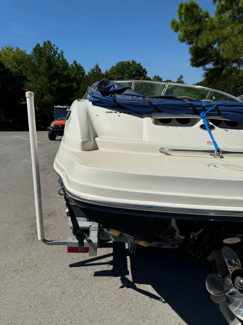 Slide: The Image of 2004 Sea Ray 200 Sundeck boat on trailer, parked outdoors with trees in background. - 4