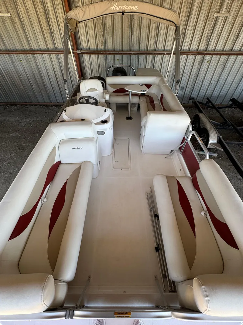Slide: The Image of 2015 Hurricane Fun Deck 196 boat with white and red seating, stored indoors. - 6