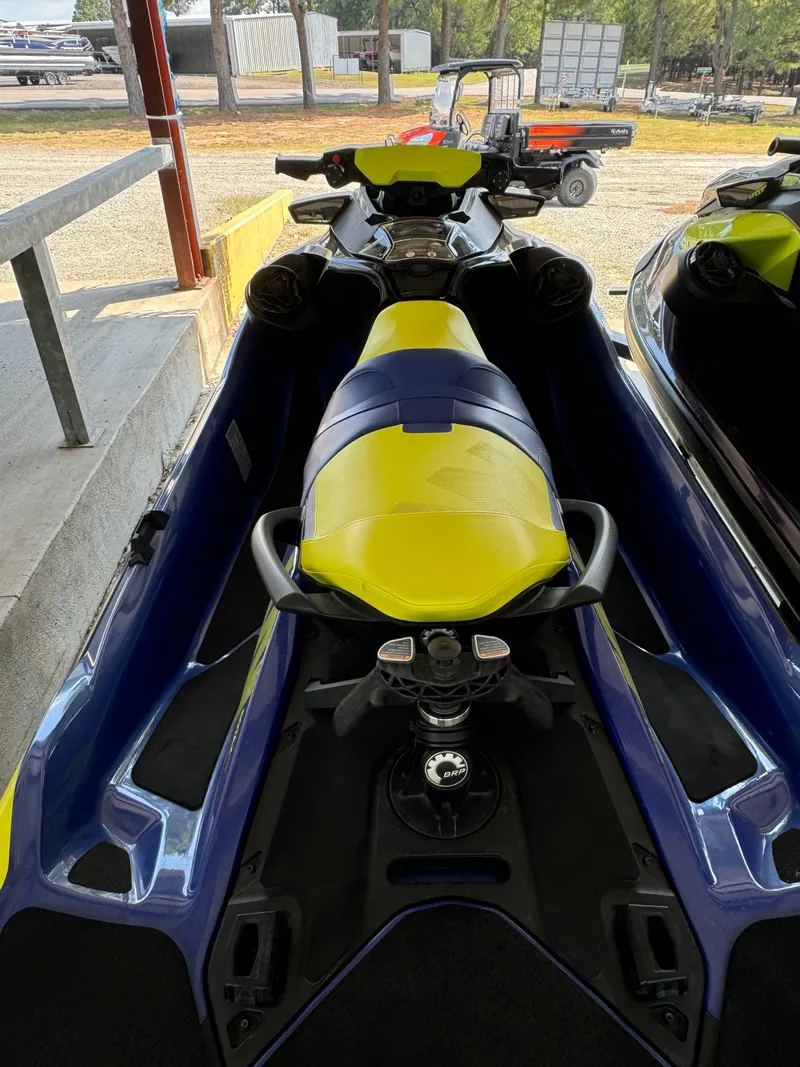 Slide: The Image of 2021 Sea-Doo Wake Pro 230 jet ski with yellow and blue seat, parked in a lot. - 6