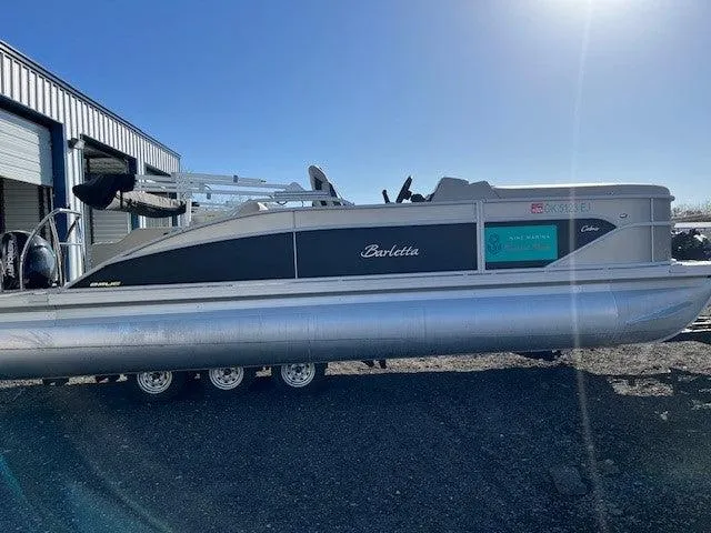 Slide: The Image of 2023 Barletta Cabrio 22UC pontoon boat parked outdoors in sunlight. - 2