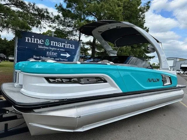 Slide: The Image of 2024 Avalon Quad Lounge Windshield boat at marina, featuring sleek design and vibrant blue color. - 10